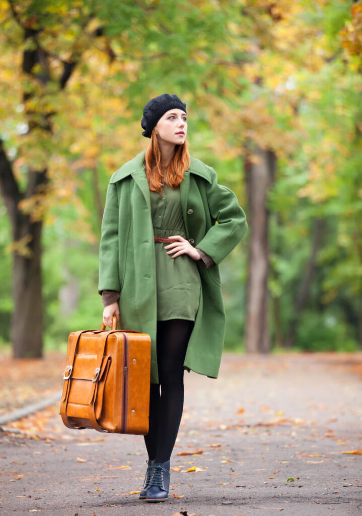 Kobieta w jesiennej stylizacji z zielonym płaszczem i sukienką