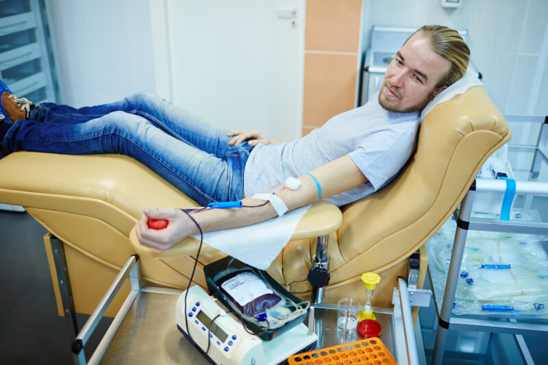 Mężczyzna leżący na fotelu w gabinecie lekarskim podczas oddawania krwi