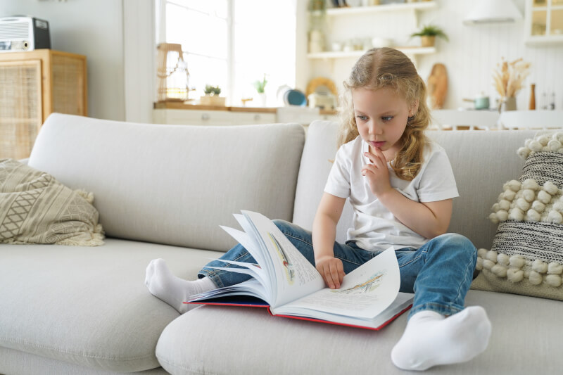 dziecko czytające książkę na kanapie