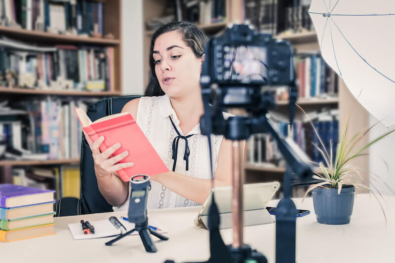 Kobieta promująca książkę przed kamerą
