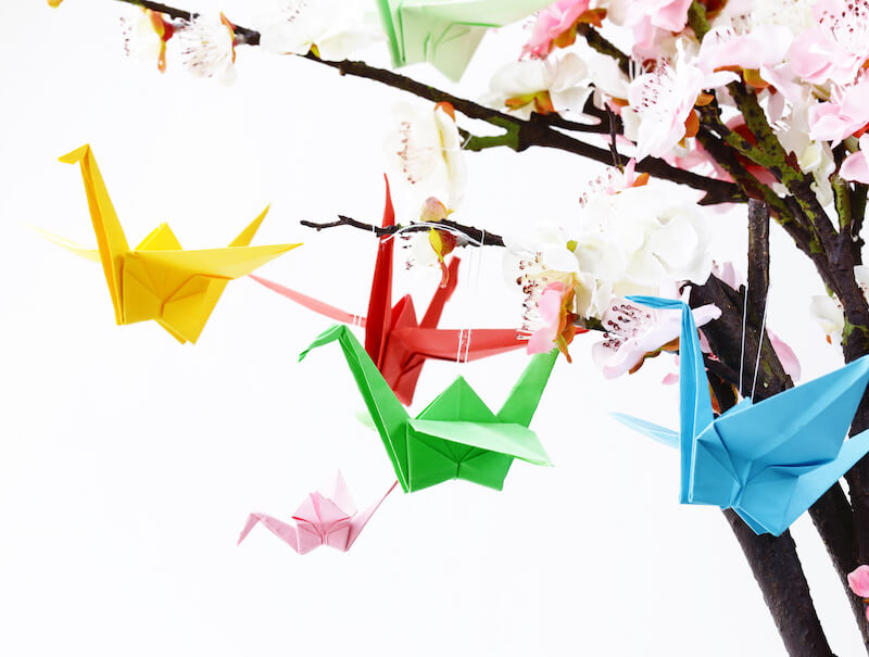 Kolorowe żurawie, origami zawieszone na gałązkach kwiata