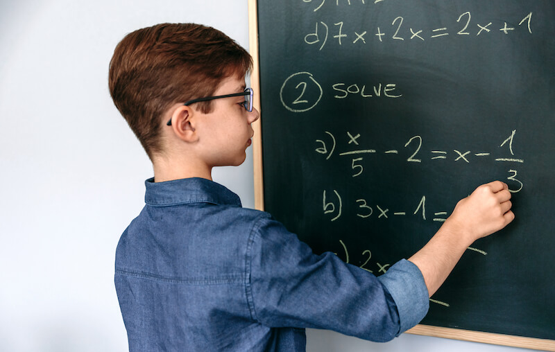 Uczeń rozwiązujący na tablicy zadanie matematyczne