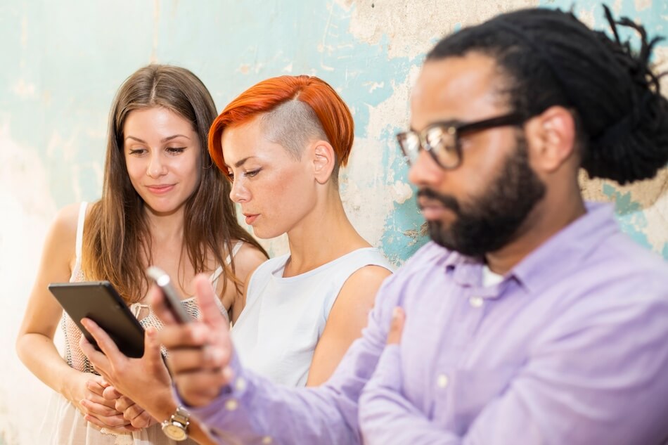 3 osoby wpatrzone w telefony trzymane w dłoni
