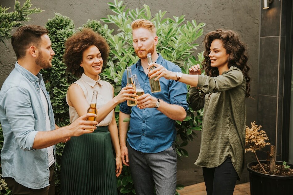 Grupa osób z butelkami piwa w dłoni podczas wznoszenia toastu