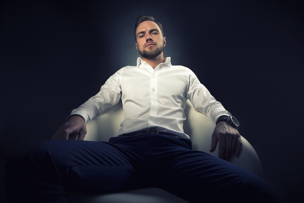 Pewny siebie, elegancko ubrany mężczyzna rozłożony na fotelu