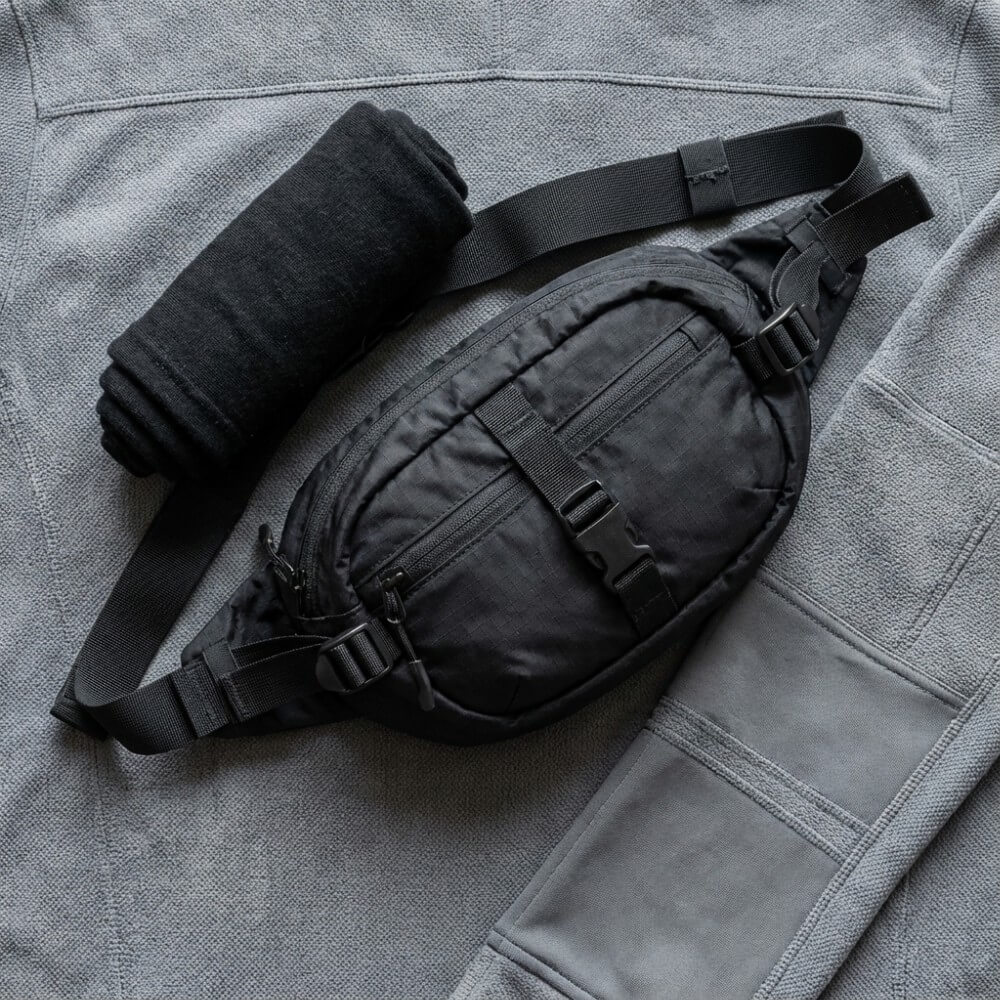 Zdjęcie zbliżeniowe akcesoriów modowych, w tym torby crossbody i kominiarki na tle materiału