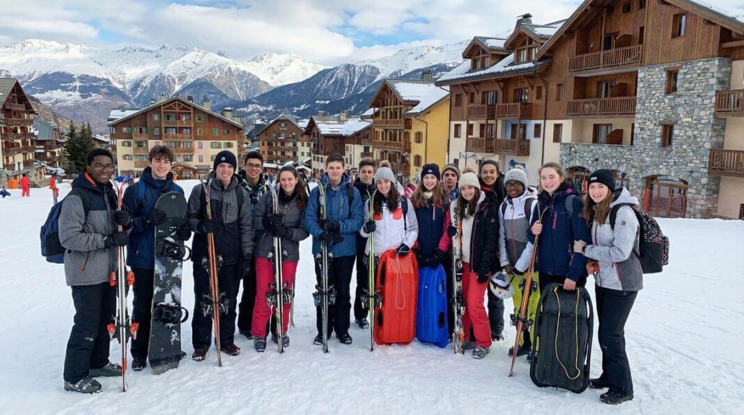 Nastolatkowie z zimowym sprzętem przed ośnieżonymi górami w Europie