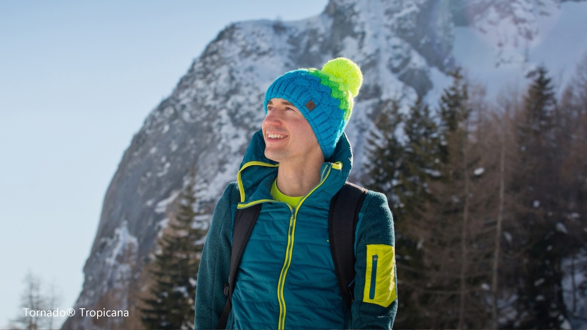 Kamil Stoch w zimowym ubraniu i czapce na tle gór